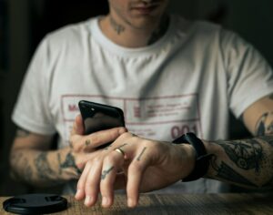 man in white crew neck t-shirt holding black smartphone